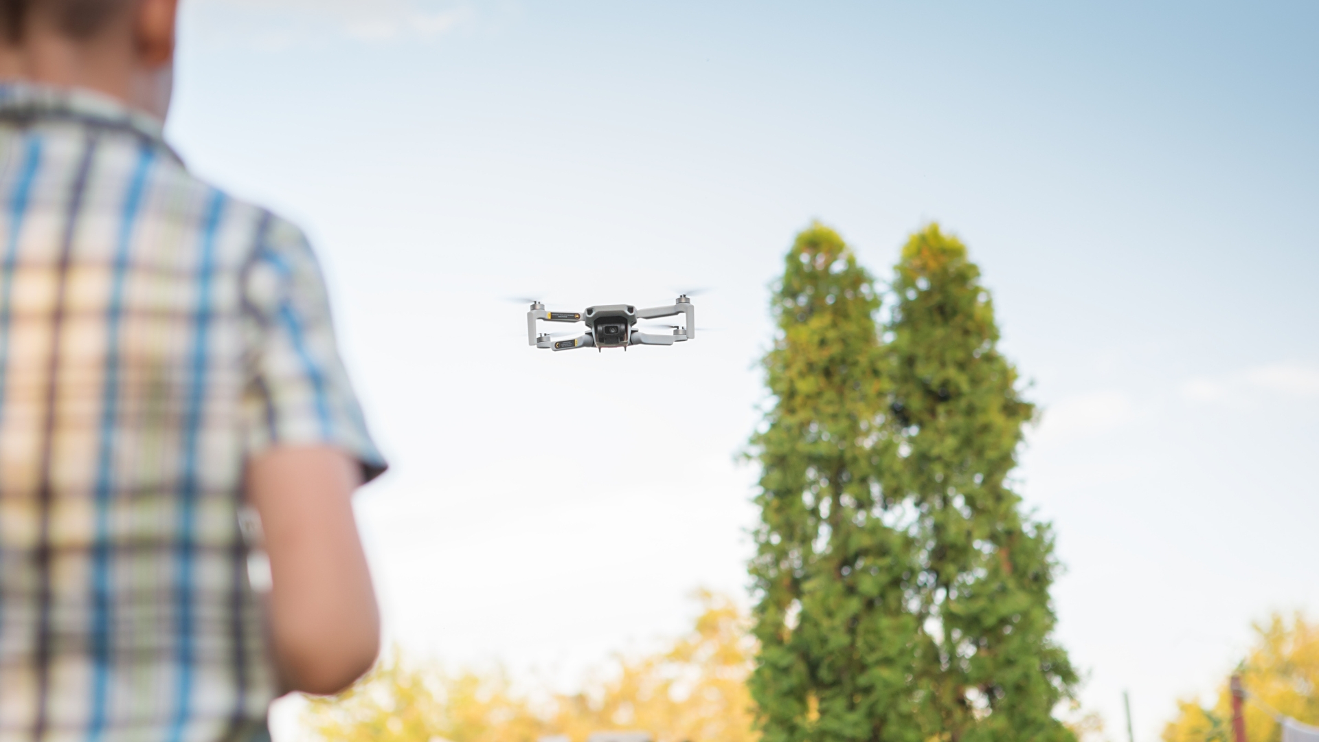 Person in a shirt flying a drone in park with trees